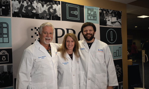 3 Researchers standing in front of LPRC backdrop wearing lab coats